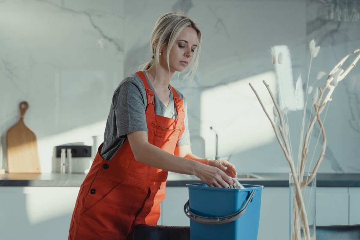 Profissional de limpeza fardada a trabalhar numa cozinha